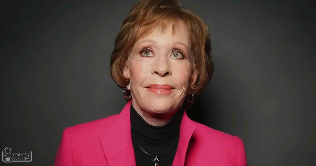 An older adult female wearing a bright pink blazer with notched lapels and black turtleneck, holding 'Madly Odd' text in a studio setting.