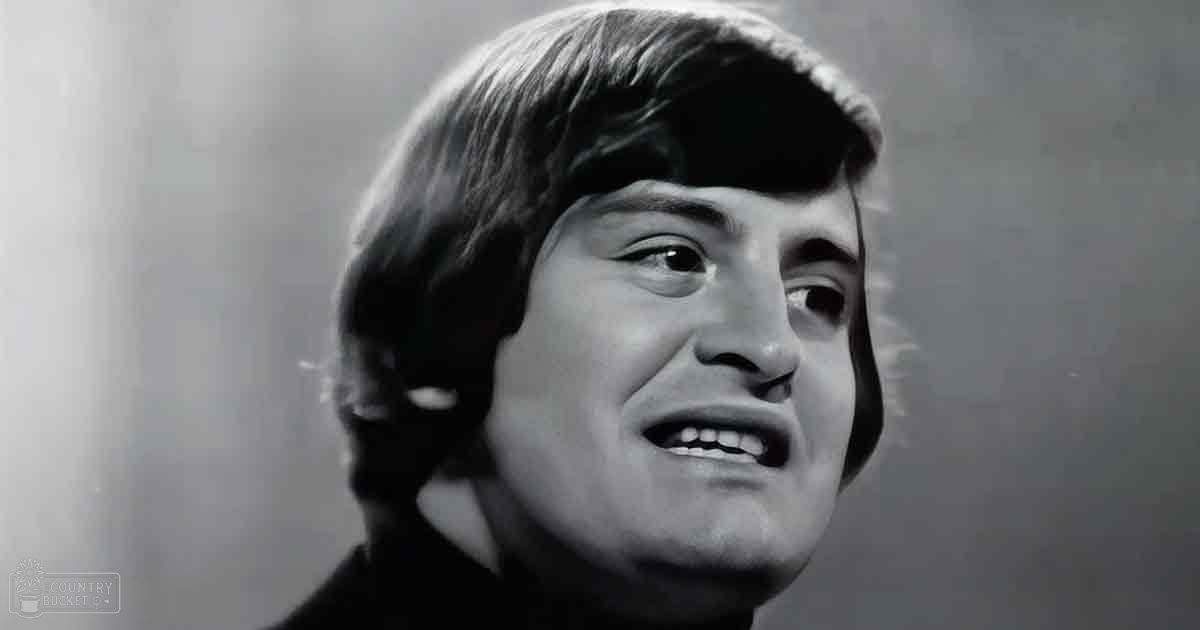 Young adult male in dark-colored turtleneck sweater indoors with natural light from one side.