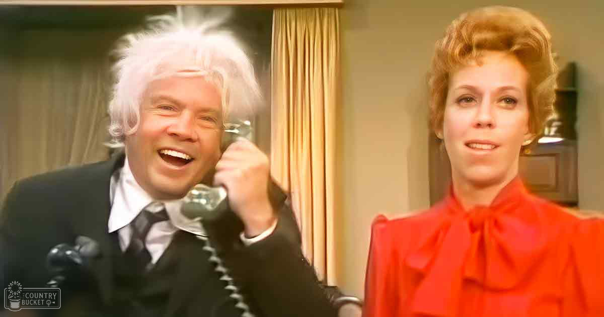 A middle-aged male in a black patterned tie and white shirt holding an older-style telephone receiver stands beside another middle-aged woman in a red garment with a bow at the neckline, both indoors in what appears to be an office or home environment.