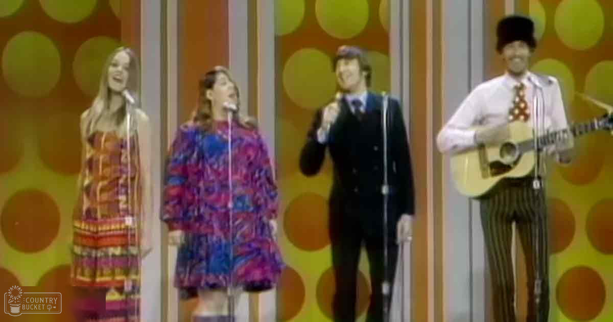 A musical performance setup with performers on stage; microphones and patterned wall suggest an indoor studio environment.