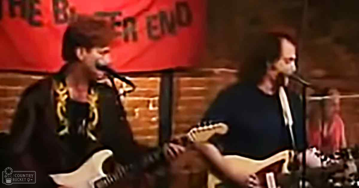Young adult males performing at 'The Better End,' wearing casual T-shirts and holding electric guitars, in an indoor venue with brick walls.