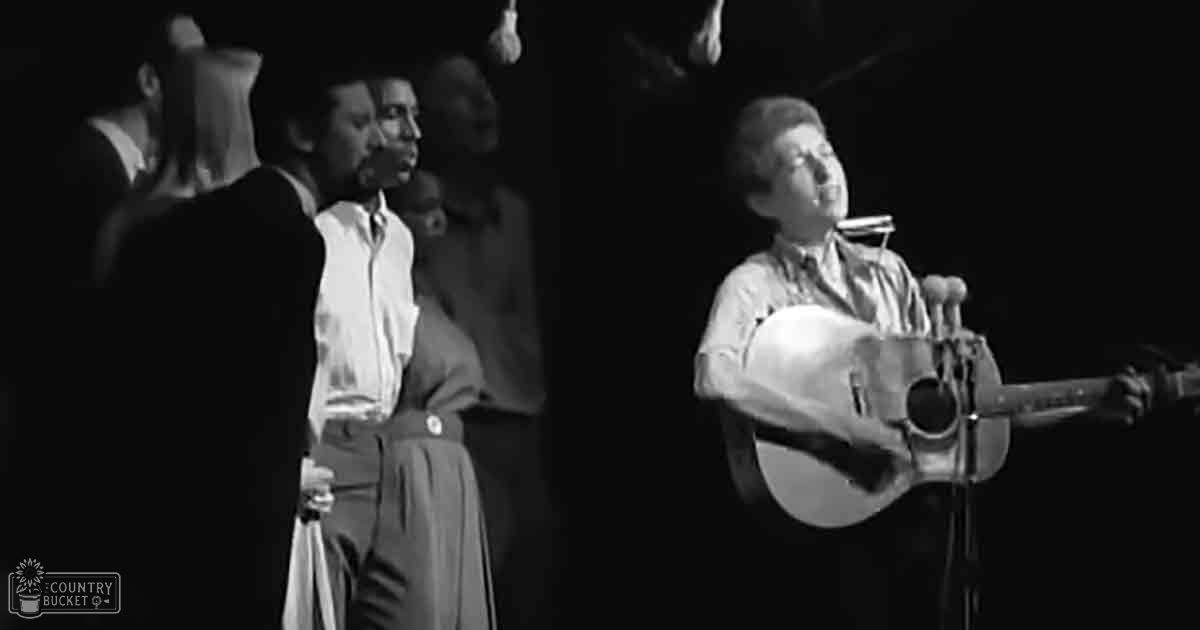 A mid-20th-century male performer in a dark suit jacket sings into a microphone while playing guitar, accompanied by an older adult female in casual yet formal attire at what appears to be a concert setting with stage lighting focused on the performers.