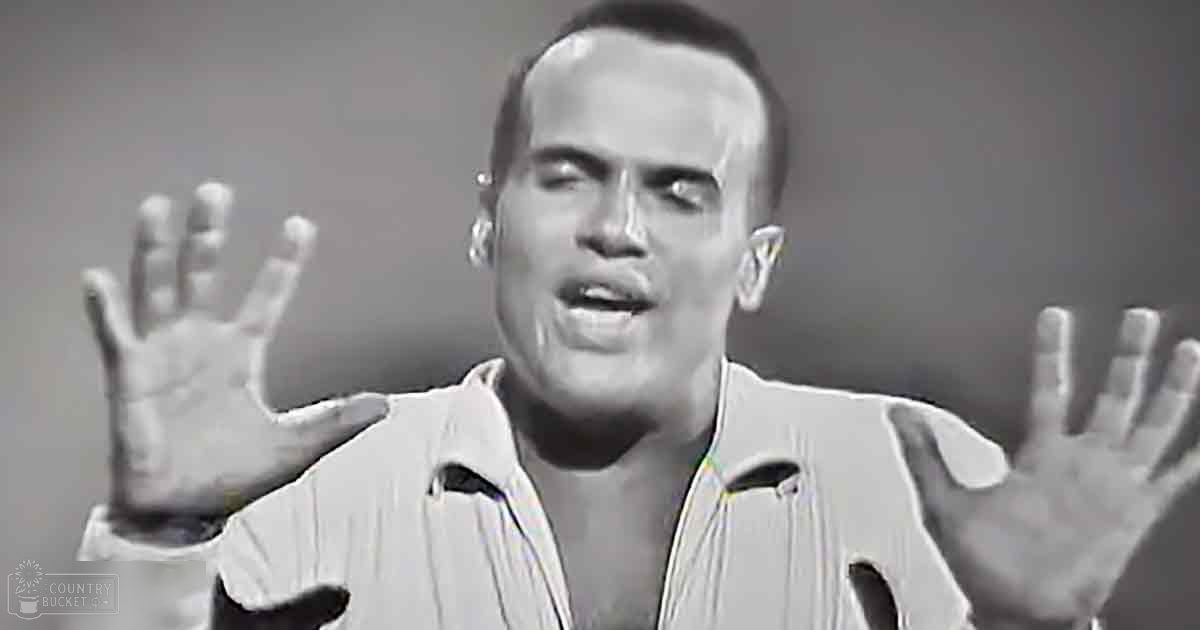 A middle-aged man wearing a white garment with cutouts, standing against a plain wall under soft lighting.