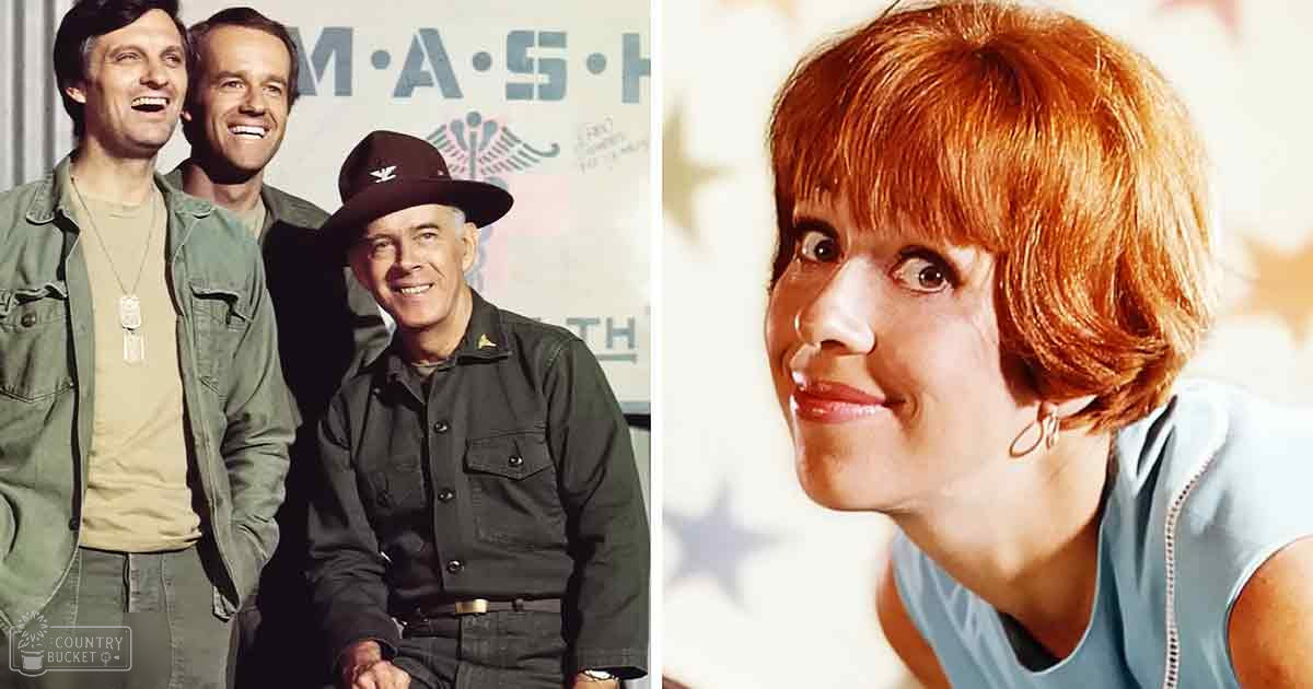 A scene from 'M*A*S*H' with a backdrop with the show's emblem and text, set indoors under bright studio lighting typical of television productions.