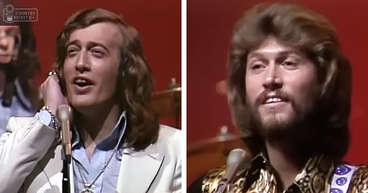Musical performance scene from the 1970s with two adult male performers on stage; one wearing a white blazer and another in a gold patterned shirt, set against a red backdrop.
