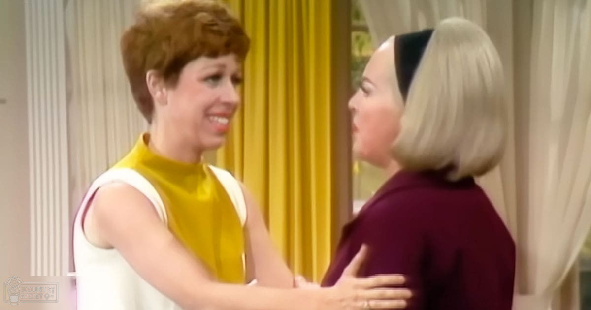 Two women, one adult female wearing a yellow and white sleeveless top with high-cut neckline indoors by natural light; another adult female in a dark purple short-sleeved top with rounded neckline and black headband or hair accessory also indoors.