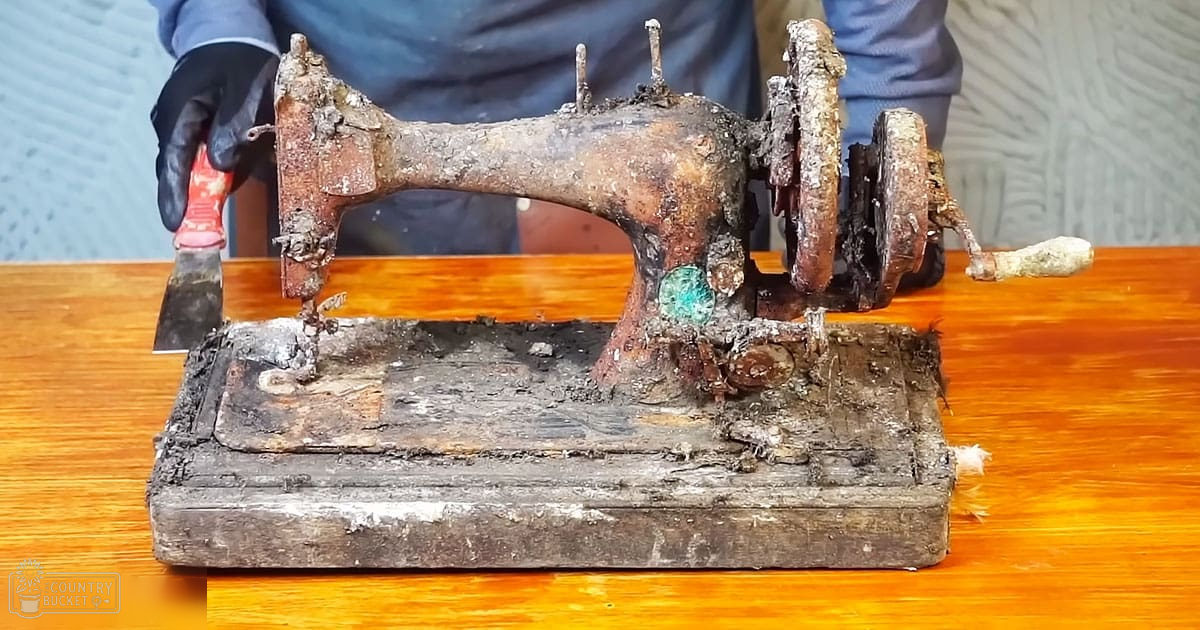 A heavily rusted sewing machine on a wooden table indoors with neutral background and even daytime lighting