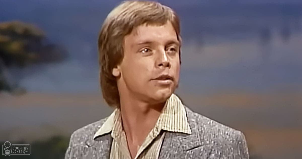 Young adult male wearing a textured blazer over a striped shirt in an arid outdoor setting with natural sunlight.