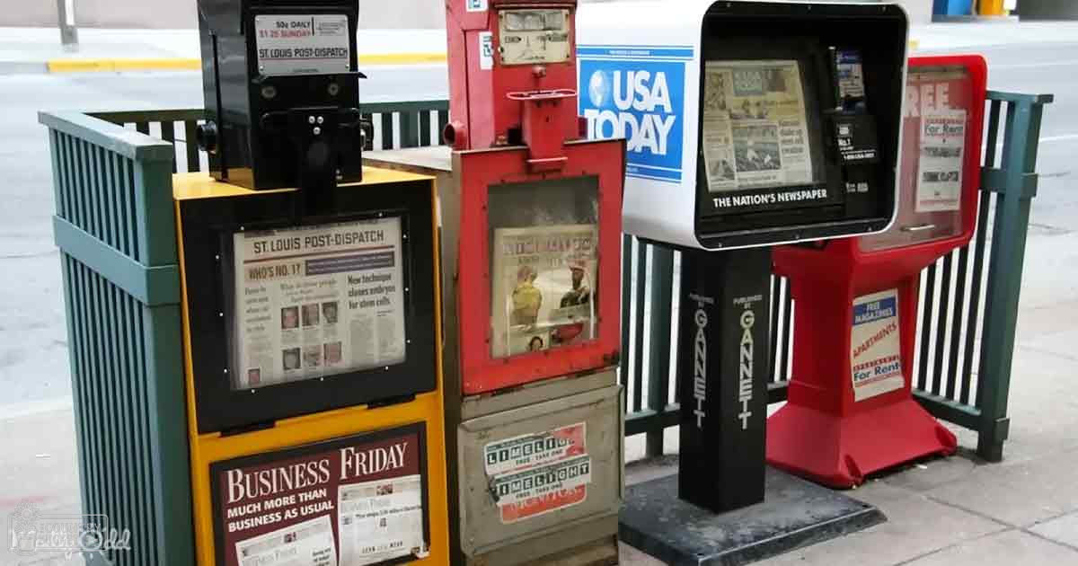 Various newspaper vending machines with colorful displays in an urban public setting