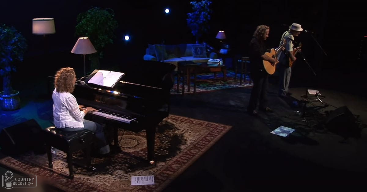 A woman playing piano in a studio setting with other musicians and stage elements visible. The indoor lighting highlights the scene's professional ambiance.