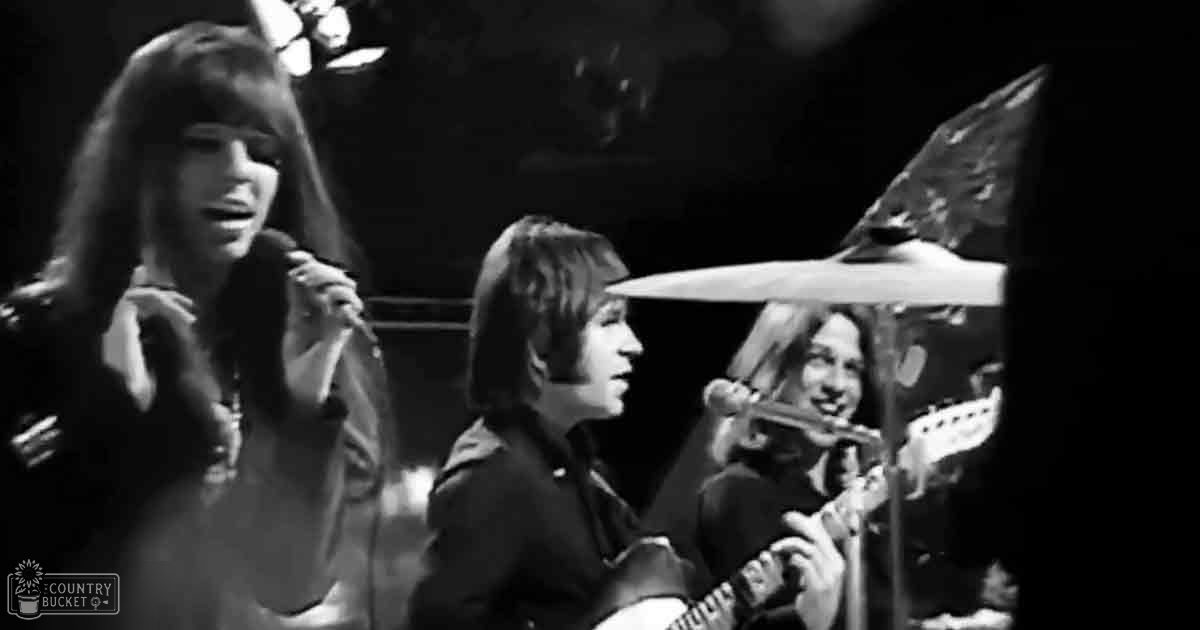 A musical performance scene with young adults in dark clothing on stage, illuminated by focused stage lights.