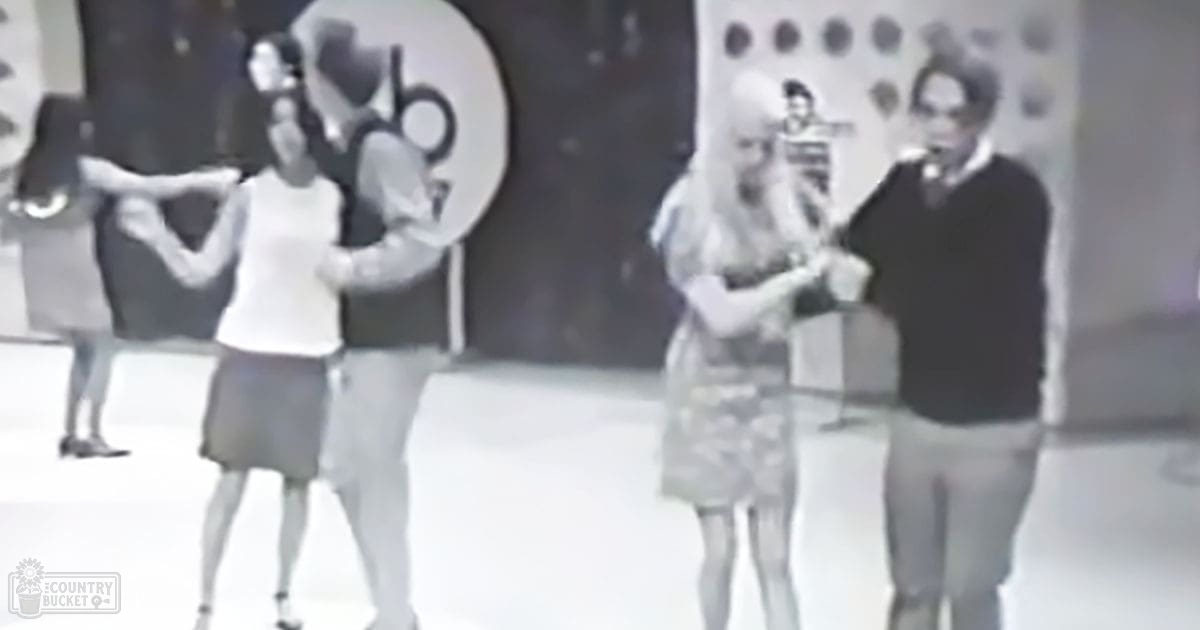 A stage performance with dancers and performers, set indoors on what looks like a mid-20th century television show backdrop.