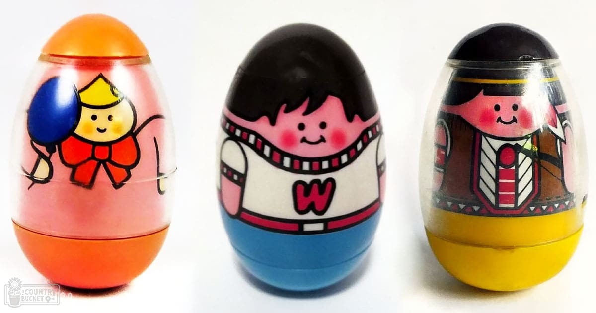 Three colorful egg-shaped toys with cartoon characters inside them are displayed against a plain white background.