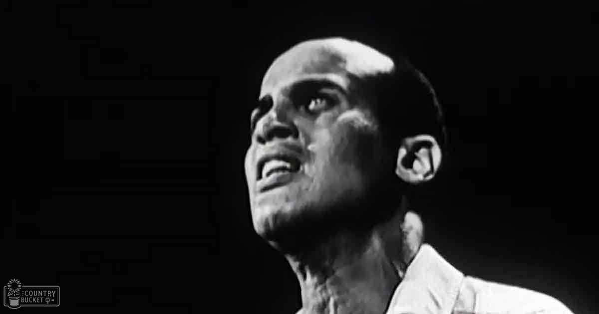 A middle-aged male wearing a white, mid-20th-century style shirt with dark surroundings and evening lighting.