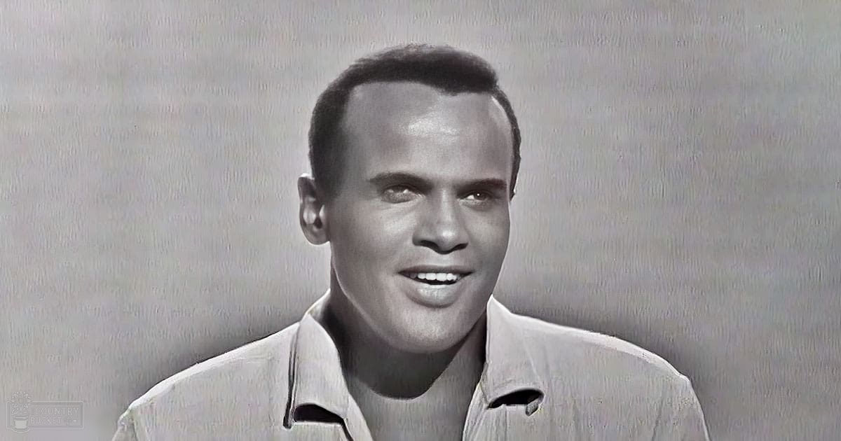 Young adult male wearing an open-collar, relaxed and casual light-colored shirt with a plain texture against a plain backdrop.