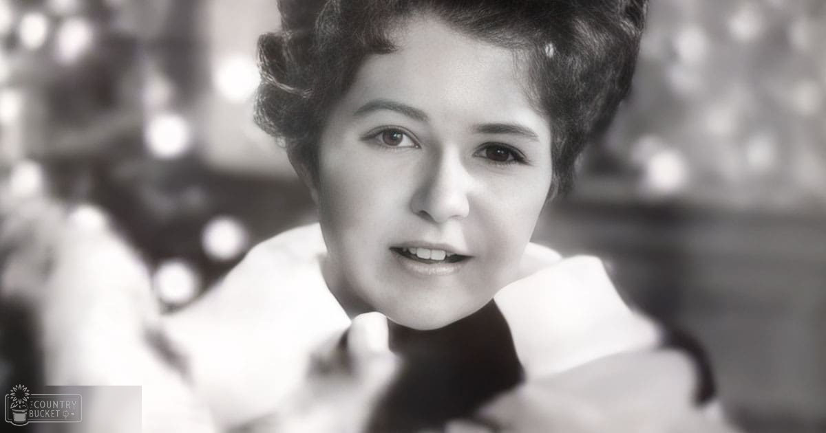 A young adult female wearing a white blouse with high collar indoors, festive lights in background suggest Christmas evening setting.