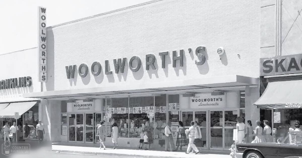 Urban Woolworth's storefront with pedestrians walking by; midday light suggests commercial buildings in an urban area, black and white image.