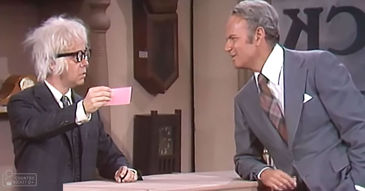 A talk show or game show set in a studio environment with two older adult male hosts wearing dark and gray suits in a daytime indoor setting.