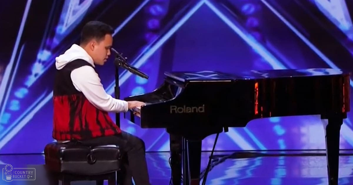 A young adult male playing piano in a talent show setting with dynamic blue and purple stage lighting.