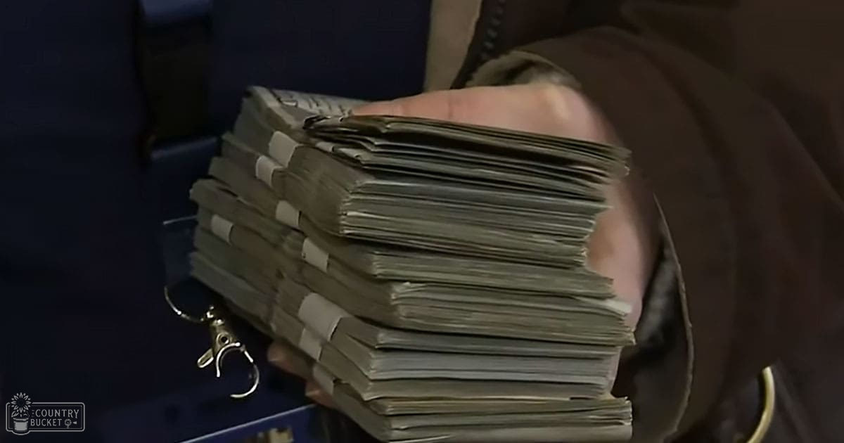 Middle-aged man holding stack of documents indoors with dim lighting, dark background, indoor scene, no animals present.