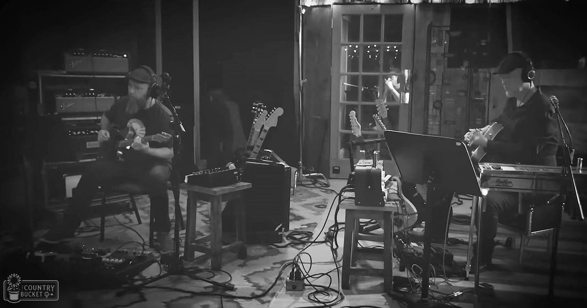 An indoor music session with two adults, one male and one female, in a studio setting with musical equipment and artificial lighting.