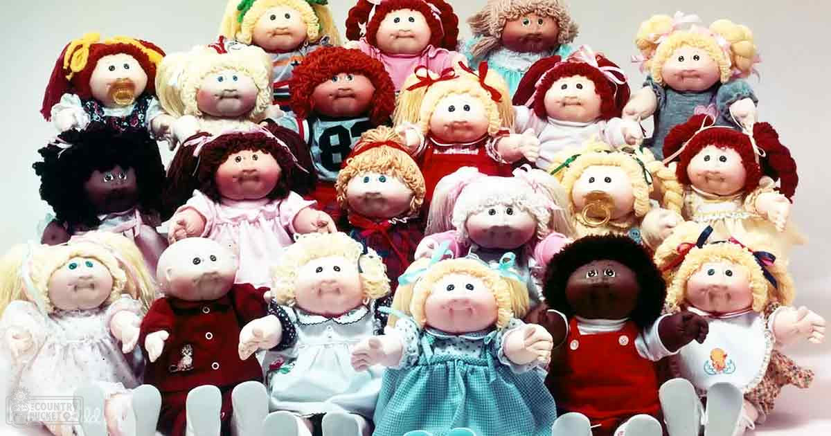 A group of infant/toddler dolls arranged indoors, dressed in various white and colorful outfits against a plain white background.