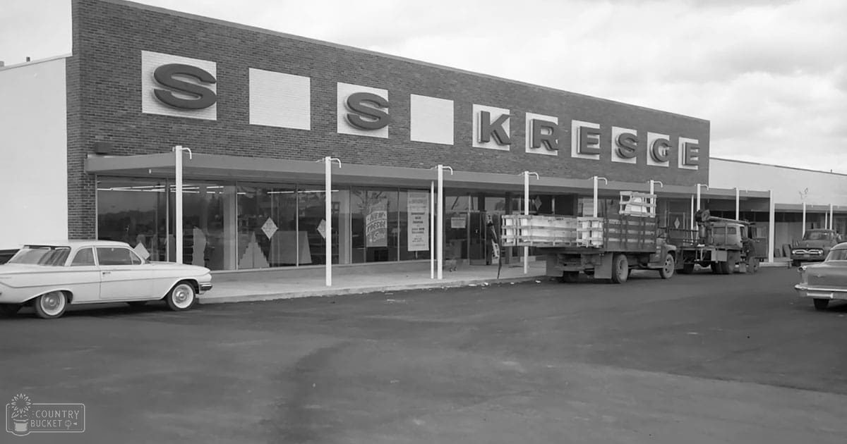 Kresge store with vintage car and trucks, urban setting, clear sky, mid-20th century black-and-white photo.