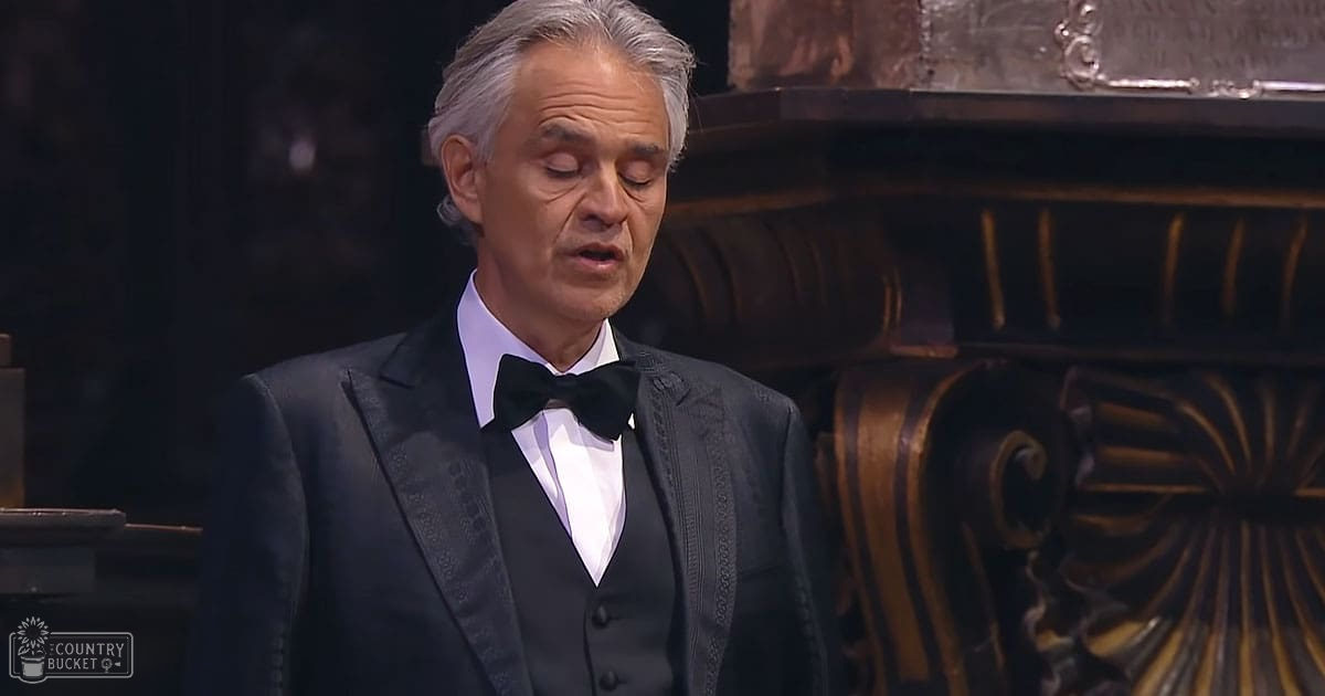 An ornate interior with a middle-aged adult male in formal wear, likely at a concert or performance under stage lighting.