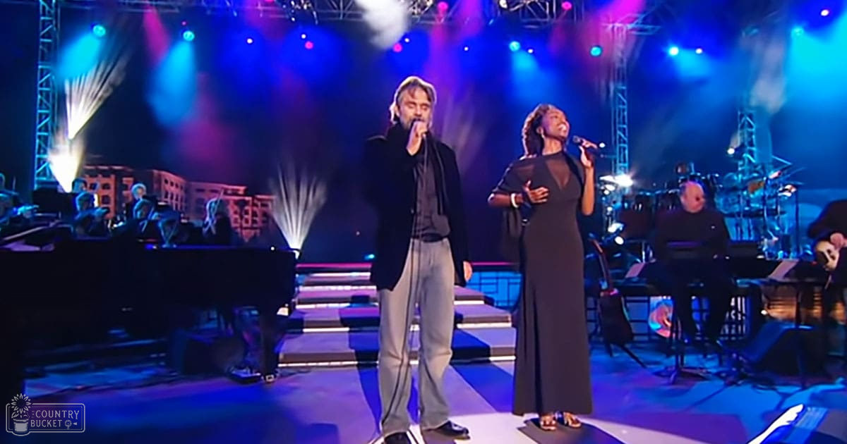A musical performance in an indoor concert setting with stage lighting predominantly blue and purple.