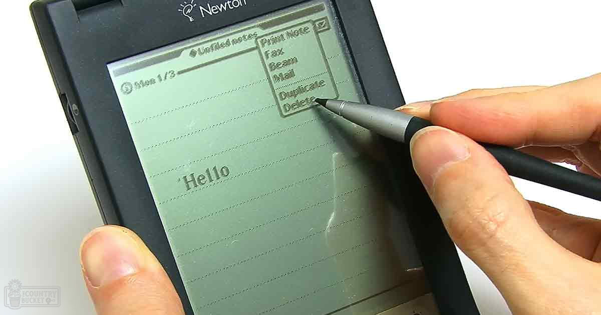 An adult using a Newton PDA with a stylus pen, likely in an indoor setting with a plain white background.