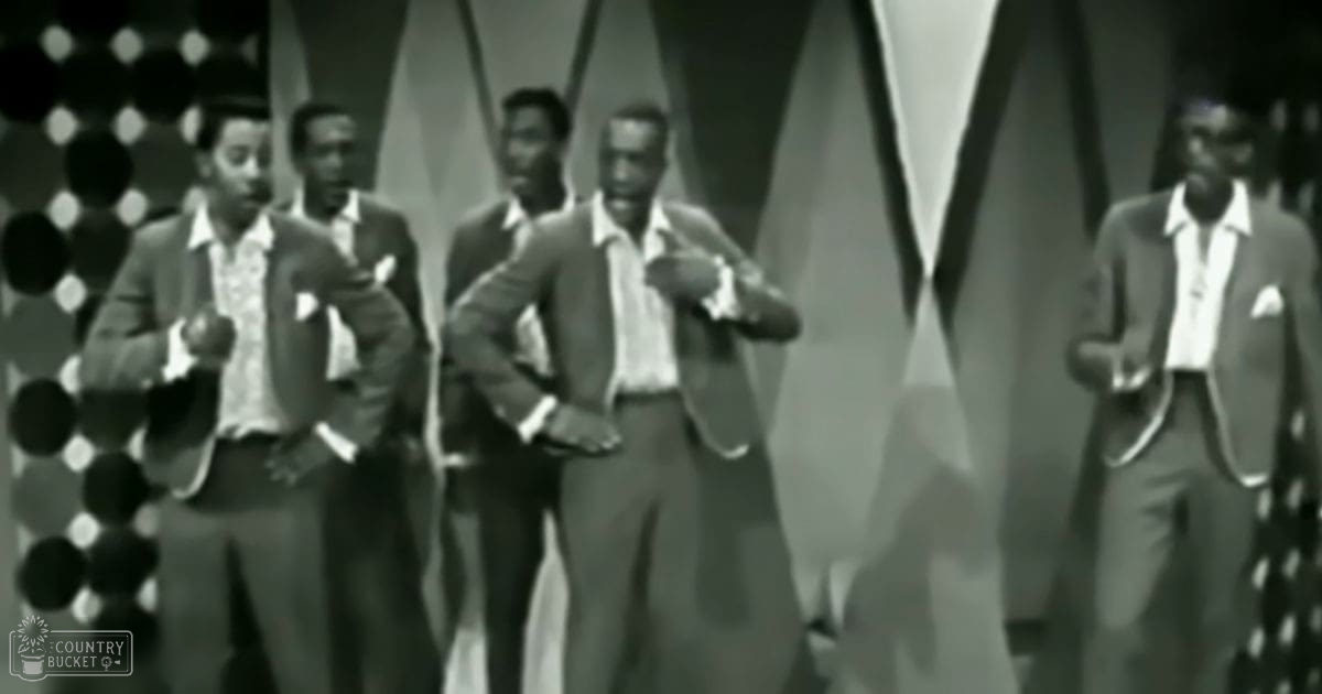A group of adult males in a studio setting, each wearing formal attire typical of mid-20th century fashion.