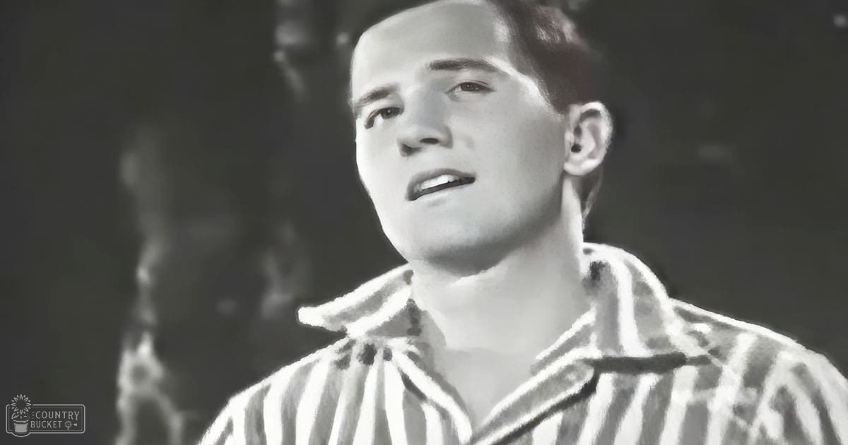 A young adult male wearing a striped shirt indoors at night with dark background