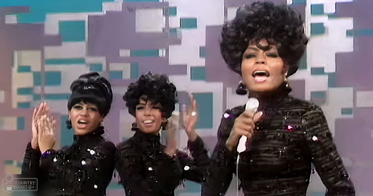 Young adult female performers in black sequined 1960s-style tops on a stage with colorful geometric backdrop, wearing gold earrings.
