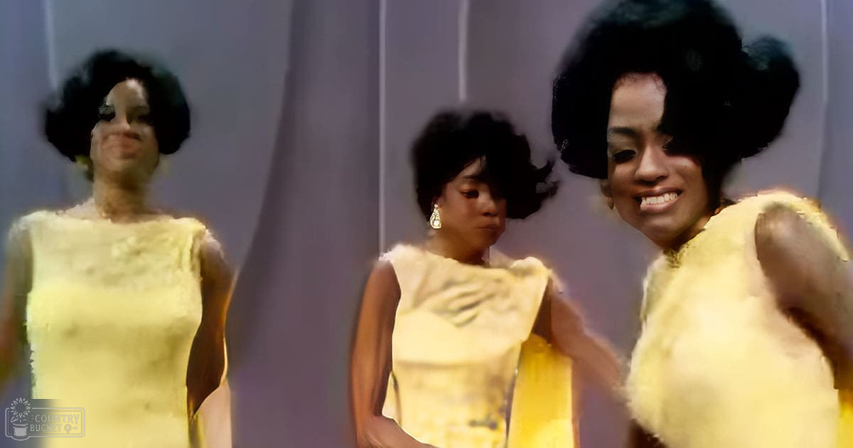 Young adult female wearing light yellow textured dress with form-fitting sleeves and loose waist, accompanied by other individuals in similar attire at an indoor formal event.