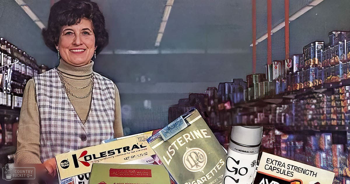 A middle-aged adult female wears a plaid vest over a turtleneck sweater in an indoor retail environment with shelves of products, including 'Kolestral,' 'Listerine,' and 'Extra Strength Capsules.'
