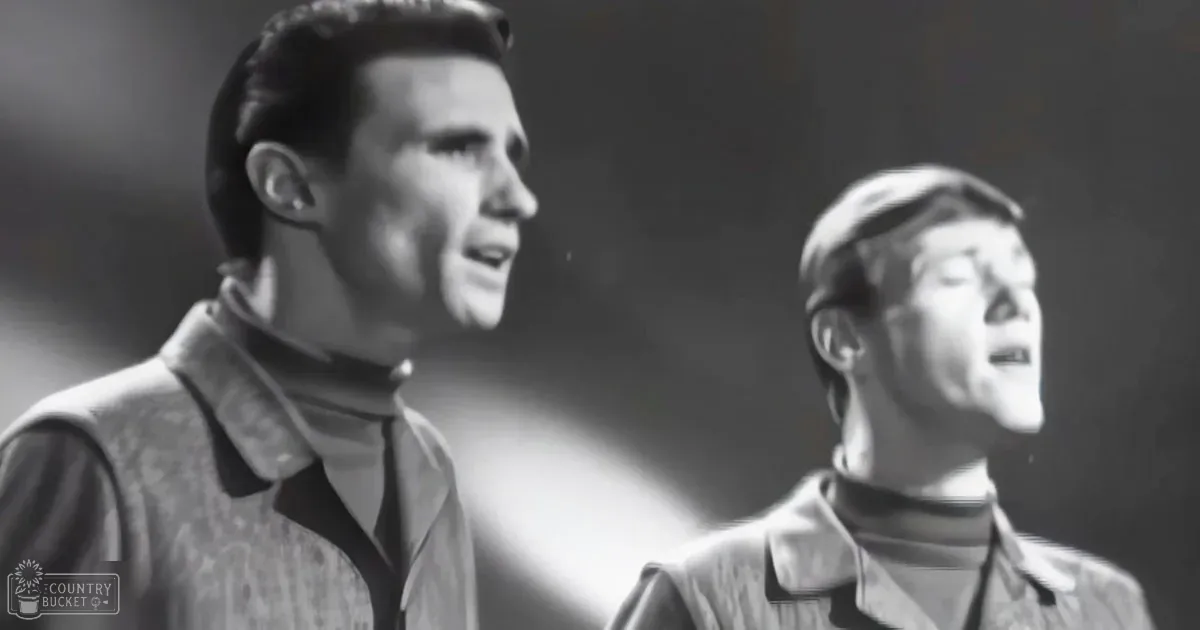 Two adult males wearing patterned jackets with high collars and long sleeves against a dark indoor background, possibly from a mid-20th-century performance setting.