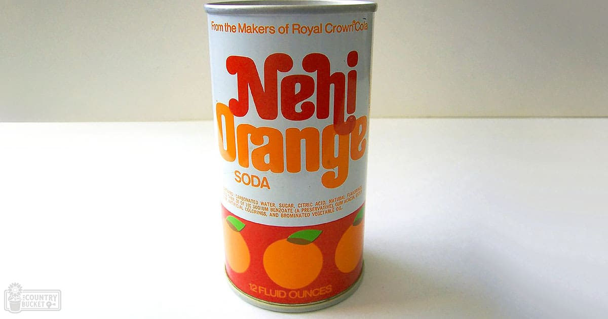 Close-up shot of a Nehi Orange Soda can with 'From the Makers of Royal Crown Cola' text, displaying ingredients including carbonated water and sugar. The can is set against a plain white background.