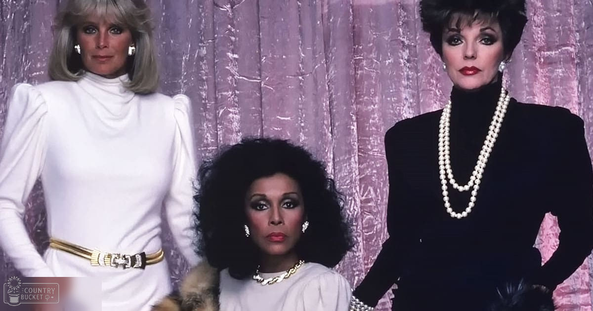 Three women in formal attire posing indoors at an event or photoshoot; white turtleneck dress with gold belt and accessories, light cotton blouse with ruffled details, black velvet dress with layered pearls.
