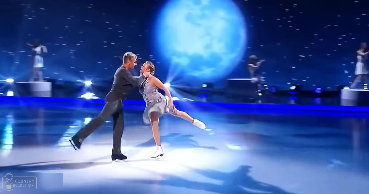 Two figure skating pairs perform on an indoor ice rink with a large illuminated blue moon backdrop, creating an ethereal winter atmosphere.