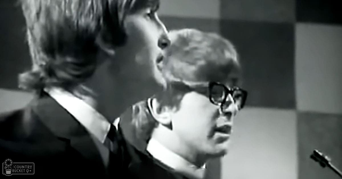 An adult male and a young person indoors with a checkered background, possibly from an event or performance venue.
