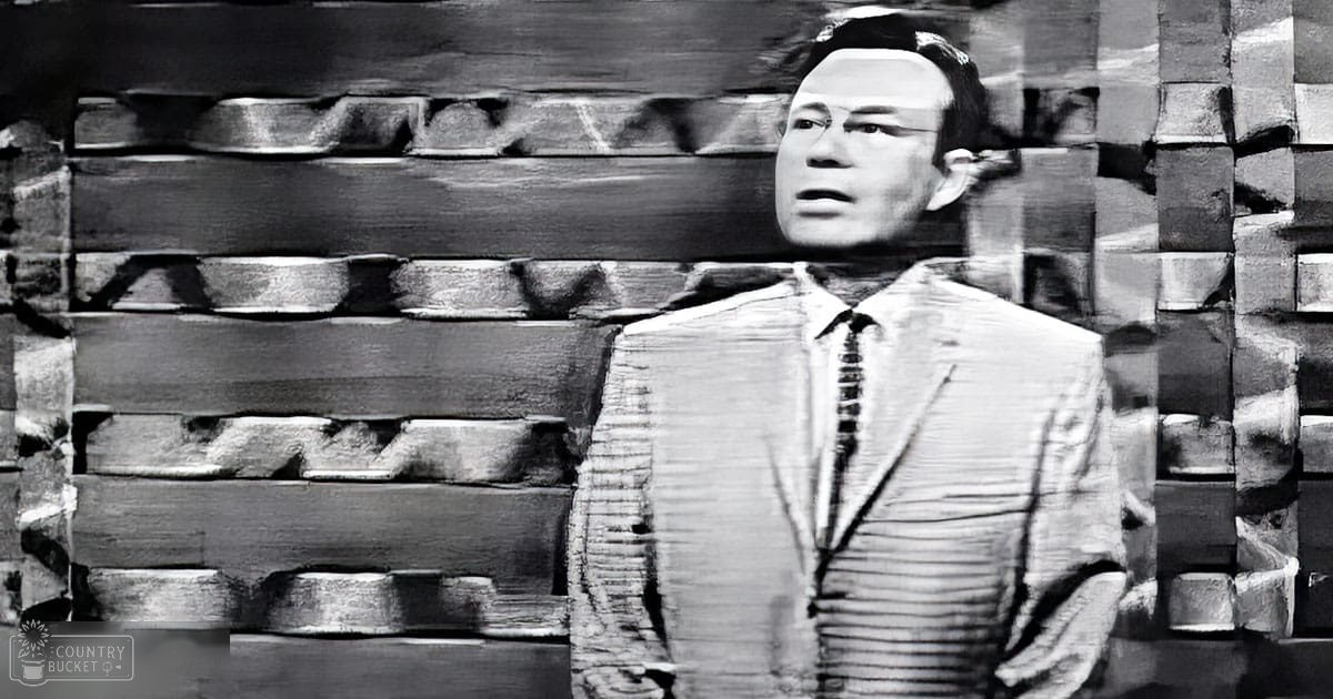 An adult male wearing a striped suit jacket with a tie, collared shirt, and textured material backdrop during daytime.