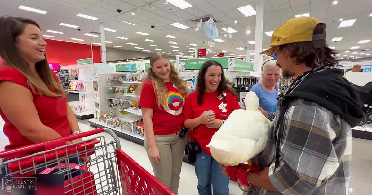 Adult females in red sleeveless tops with a circular design, adult female in a red t-shirt holding something small, adult male in a plaid jacket and yellow cap inside a retail store setting with shelves of various items.