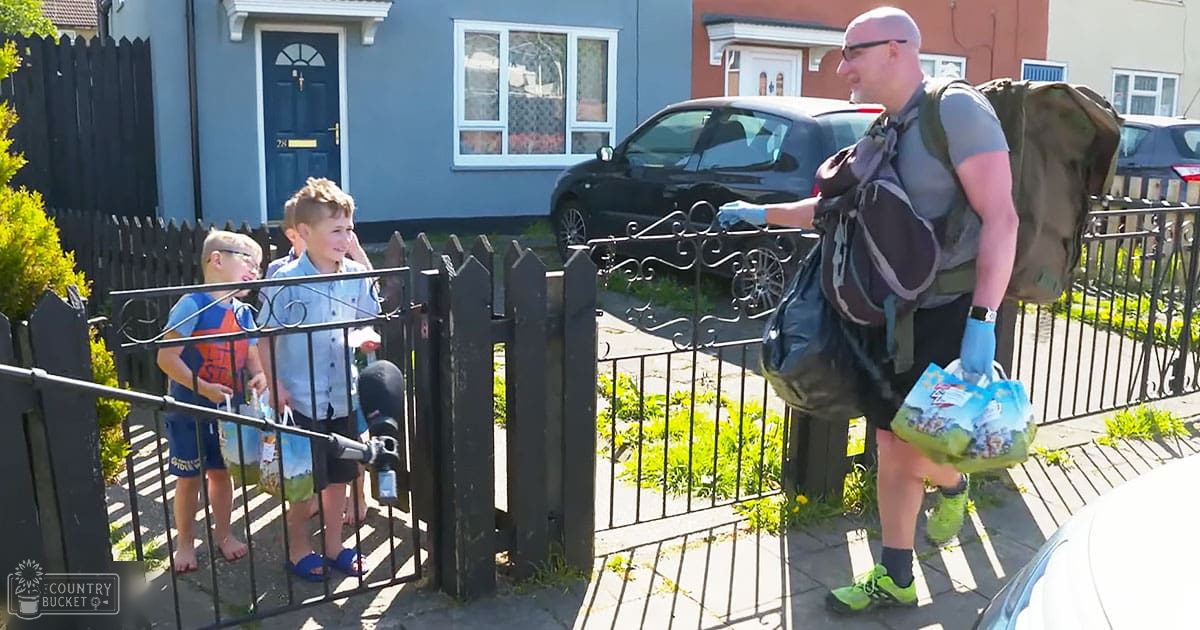 A residential neighborhood scene with a man in an adult male singer gray t-shirt and black shorts walking past two children on a sunny day.