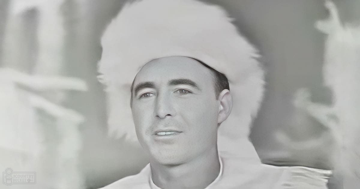 Young adult male wearing a white high-collar shirt with long sleeves, indoors with soft lighting.