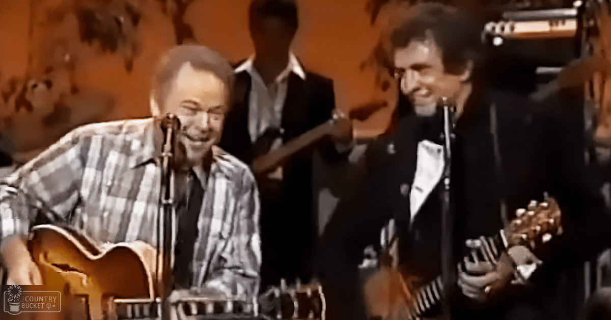 Two adult male musicians performing on a stage with microphones and warm lighting, wearing formal attire.