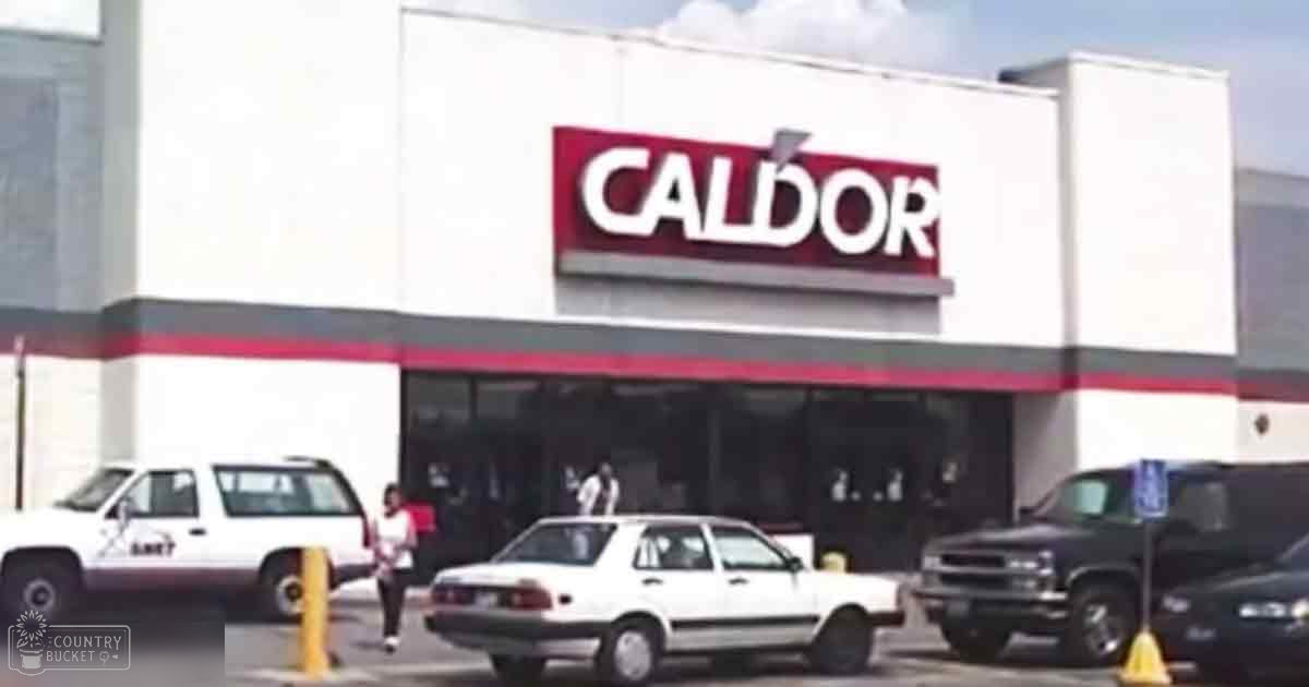Two individuals in a parking lot outside a Caldor store, white SUV with 'SHERIFF' text visible.