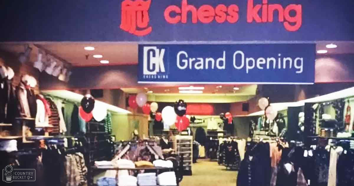 Indoor retail setting with clothing racks, balloons, evening lighting; Chess King grand opening celebration ambiance.