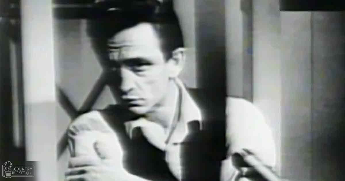 A young adult male wearing a collared shirt and tie, standing against an urban backdrop with columns, likely mid-20th century style.
