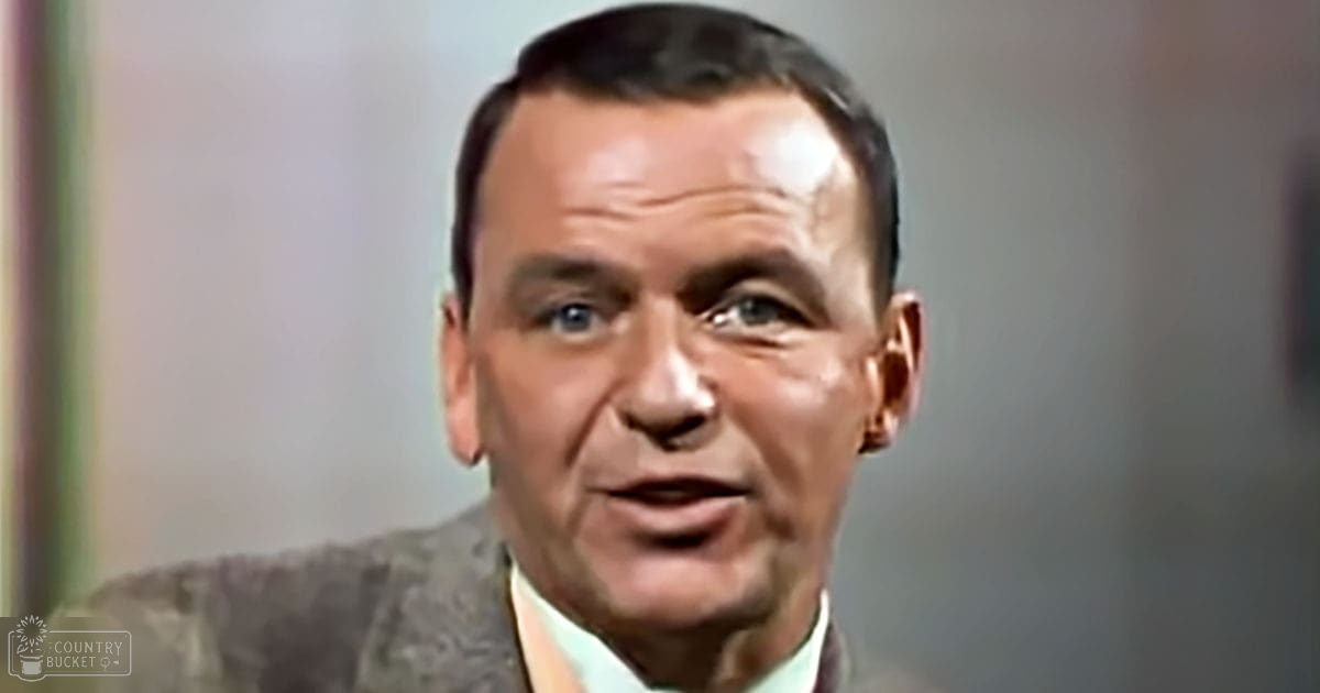 An older adult male in a professional setting wearing a dark suit jacket with a light-colored shirt underneath.