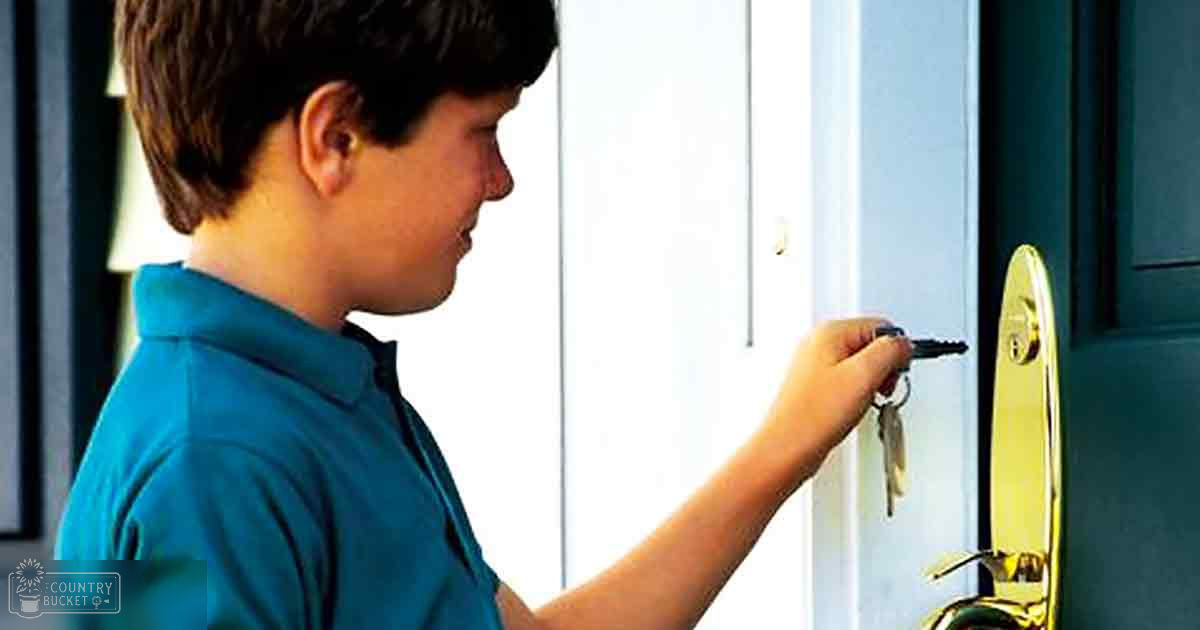A child in a teal polo shirt indoors, holding a keychain near a golden door handle with white vertical paneling.